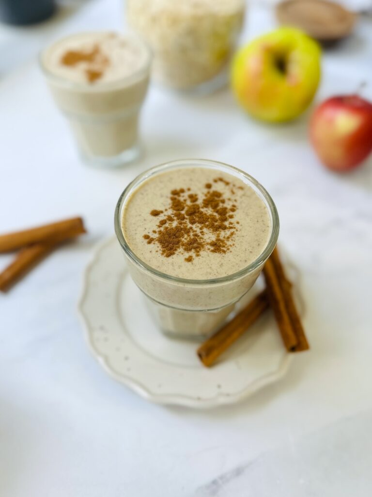 apple pie smoothie in a glass with cinnamon sticks
