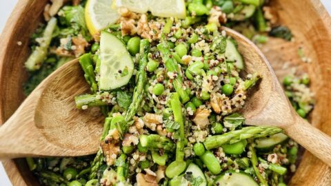 ultimate spring salad with serving spoons in wooden bowl