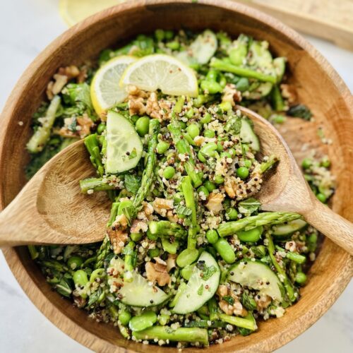ultimate spring salad with serving spoons in wooden bowl