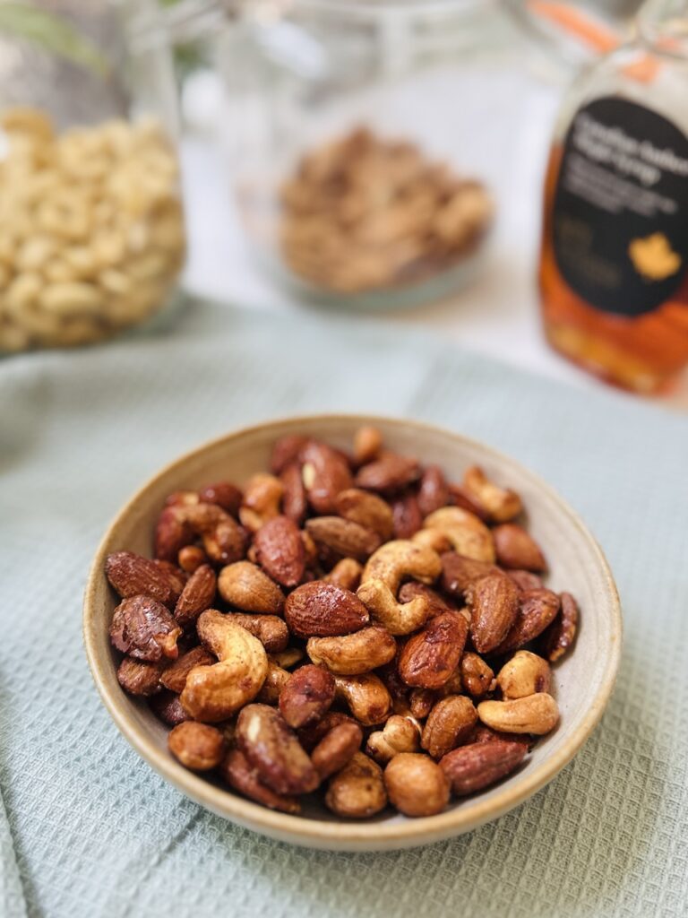 maple roasted nuts in a bowl with ingredients in background